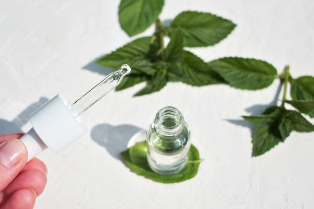 Médecine alternative, une bouteille de sérum et une pipette dans les mains d'une fille.