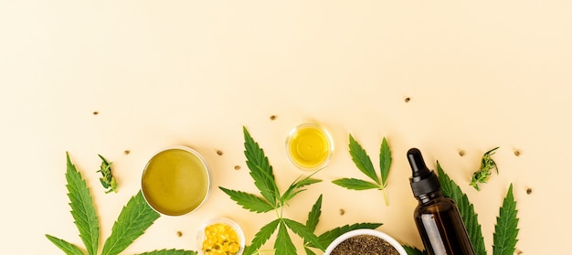 Médecine alternative, cosmétiques naturels. huile de CBD et feuilles de cannabis cosmétiques vue de dessus sur fond orange, mise à plat