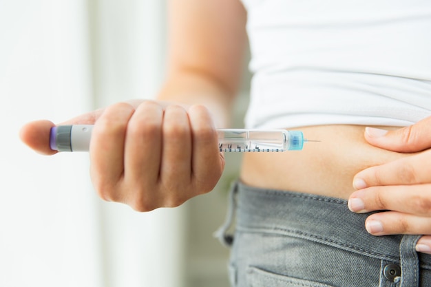 médecine, diabète, glycémie, soins de santé et concept humain - gros plan sur des mains de femme faisant une injection avec un stylo à insuline ou une seringue