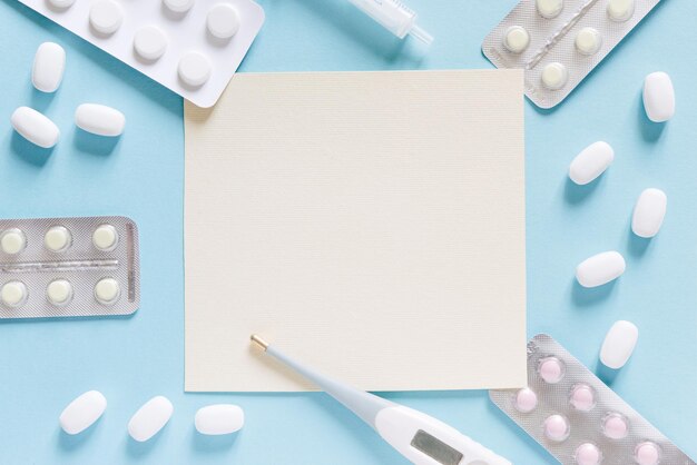 Médecine minimaliste et concept de soins de santé flatlay pilules et un thermomètre sur fond bleu