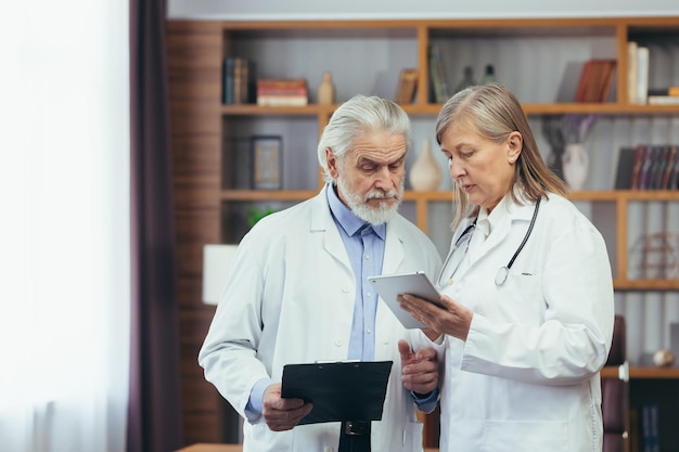 Les médecins collègues d'une personne et d'une femme aux cheveux gris sont des médecins qui pratiquent dans un cabinet médical classique d'une clinique