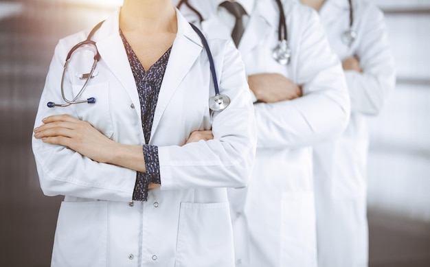 Médecins debout en équipe avec les bras croisés dans une clinique ensoleillée. Concept d'aide médicale, d'assurance et de médecine.