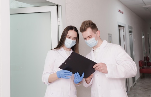 Les médecins discutent du rapport médical à l'hôpital Une jeune femme médecin et un homme médecin vérifient le rapport clinique du patient en ligne Personnel médical debout dans le couloir d'une clinique privée