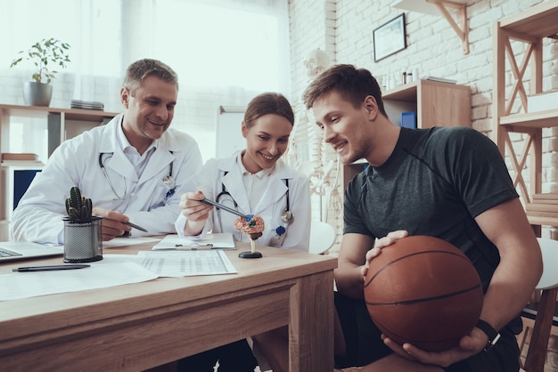 Médecins Masculins Et Féminins En Clinique Avec Basketteur.