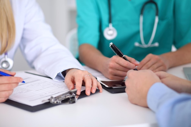 Les médecins et les patients discutent de quelque chose, juste les mains à la table.