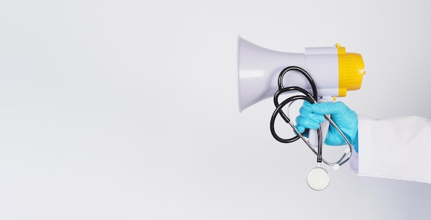 Les médecins portent des gants en latex et tiennent un mégaphone et un stéthoscope sur fond blanc.