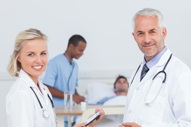 Médecins souriants debout devant le patient