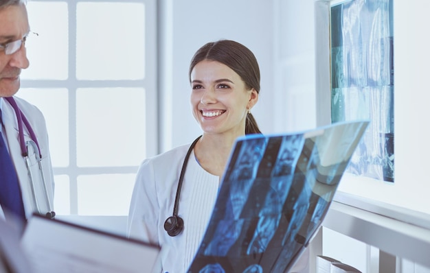 Médecins souriants discutant du diagnostic du patient en regardant les radiographies dans un hôpital