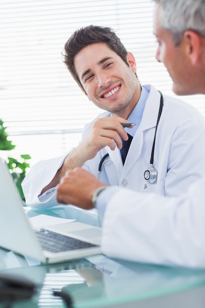 Médecins souriants parler de quelque chose sur leur ordinateur portable