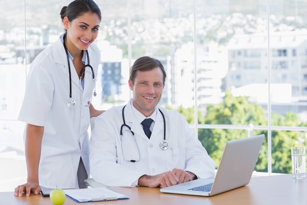 Médecins souriants posant ensemble dans leur bureau