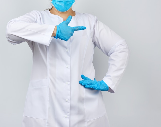 Medic femme en blouse blanche avec des boutons sur ses mains, portant des gants stériles bleus