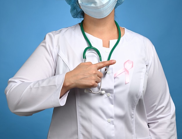 Medic femme en blouse blanche, ruban rose épinglé à la robe, symbole de la lutte contre le cancer du sein en octobre, gros plan