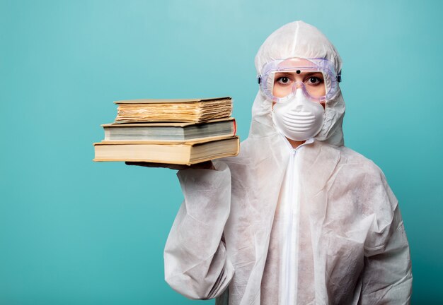 Medic femme portant des vêtements de protection contre le virus détient des livres