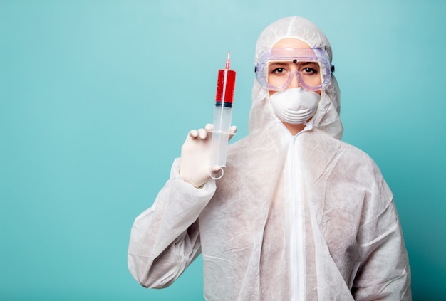 Medic femme portant des vêtements de protection contre le virus avec une grosse seringue