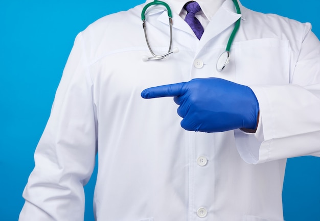 Medic homme en blouse blanche avec des boutons, sur les mains avec des gants stériles bleus