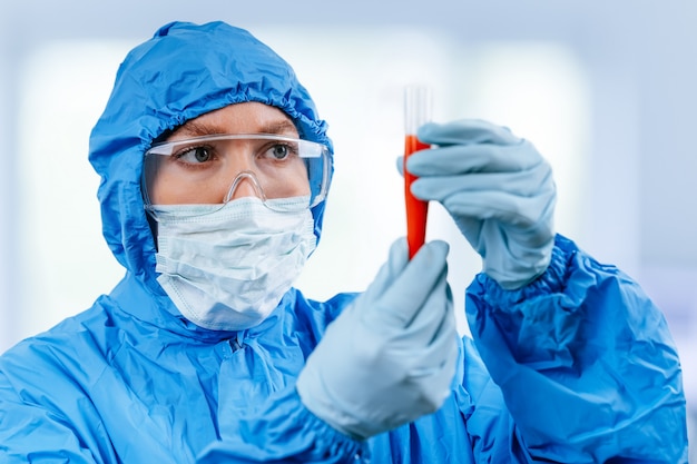Medic en tenue de protection hazmat est titulaire d'un tube à essai avec un échantillon de sang positif de coronavirus de Wuhan, en Chine. Pandémie nCoV 2019. arrêter le coronavirus. MERS.