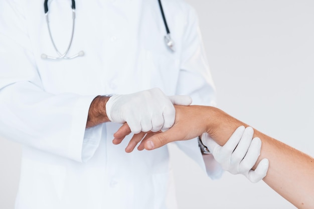 Medic travaille avec la main du patient Vue rapprochée des particules du jeune homme qui se tient à l'intérieur sur fond blanc