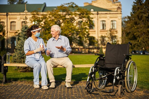 Medic et vieil homme assis à l'extérieur de la maison de retraite