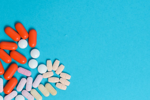 Médicaments colorés Pilules en forme de cœur isolées sur fond bleu supplément de vitamines coloré