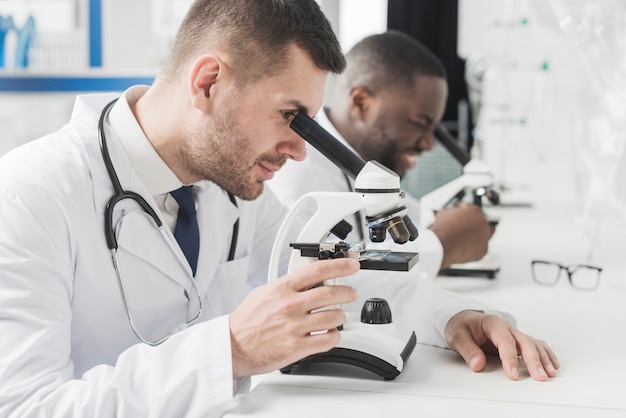 Médicaments multiraciales joyeux avec des microscopes