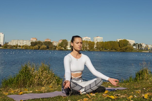 Méditation dans le parc de la ville Une jeune femme est assise sur un tapis et se détend après le yoga