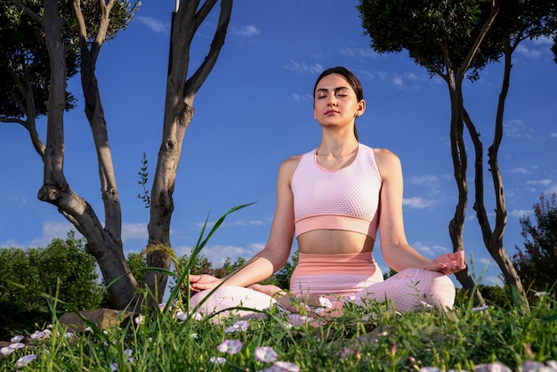 Médite dans la nature. Une fille est engagée dans le yoga dans la rue, dans un survêtement rose fait divers exercices et poses de yoga