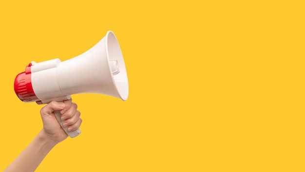 Mégaphone dans les mains de la femme sur un fond blanc