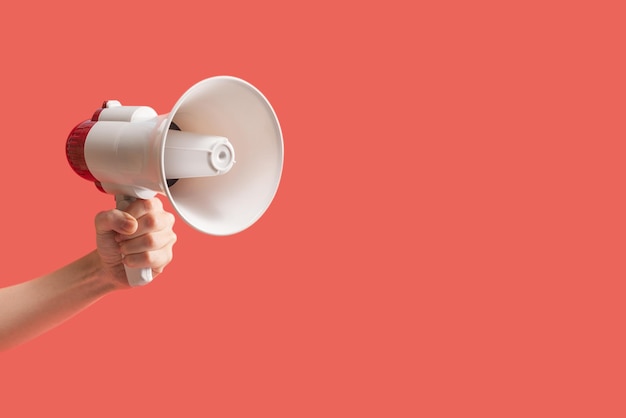 Mégaphone dans les mains de la femme sur fond rouge. Espace de copie.