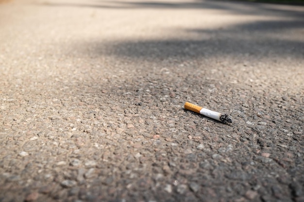 Photo mégot de cigarette jeté sur la chaussée en asphalte mauvaise habitude dangereuse pour la santé et la pollution de l'environnement