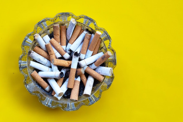 Mégots de cigarettes dans un cendrier en verre