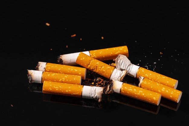 Les mégots de cigarettes sur la surface noire close up