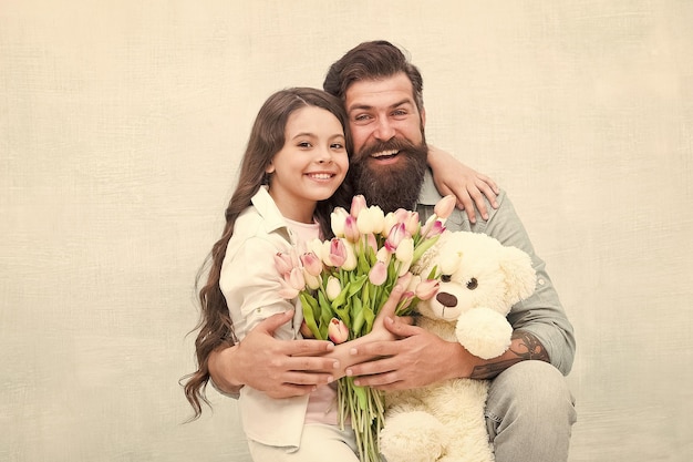 Le meilleur jour de tous les temps Une famille heureuse célèbre les vacances Un petit enfant et son père tiennent des fleurs et des jouets