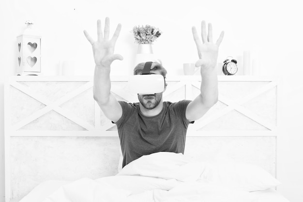 La meilleure expérience VR Beau mec portant un casque VR au lit Homme caucasien utilisant des lunettes VR dans la chambre Rendu immersif en VR