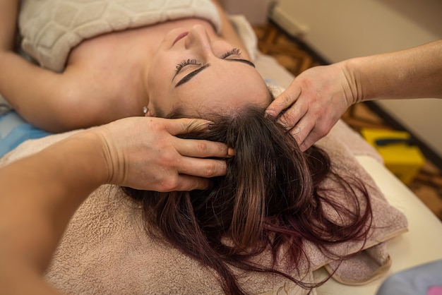 La meilleure masseuse aux mains douces masse la tête et le visage pour le meilleur client avec le visage