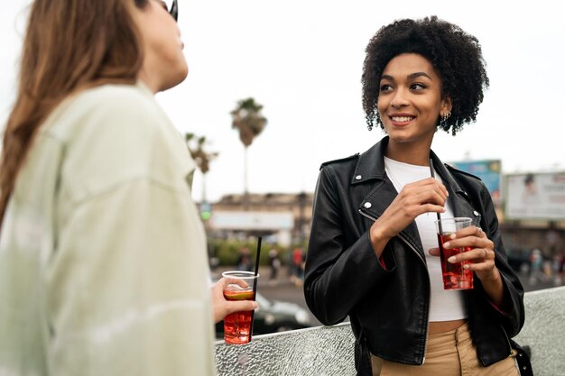 Les meilleurs amis parlent et boivent des cocktails à emporter à l'extérieur