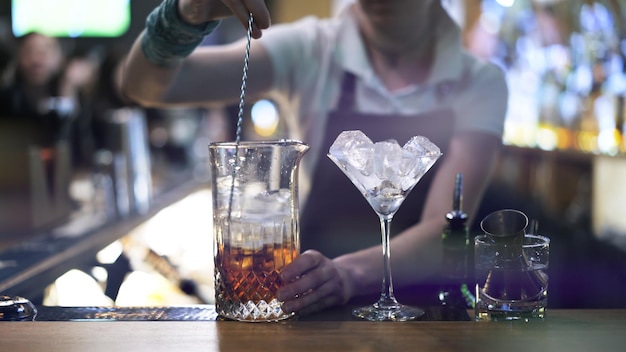 Mélange d'alcool avec des cubes de glace sur fond de barman au bar