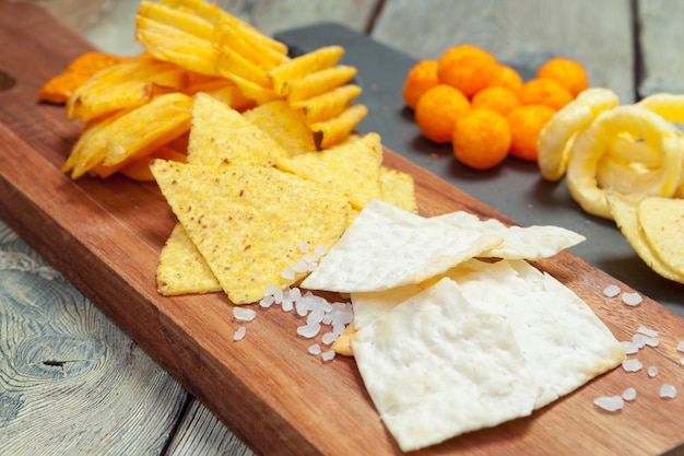 Mélange de collations: bretzels, craquelins, frites et nachos sur la table