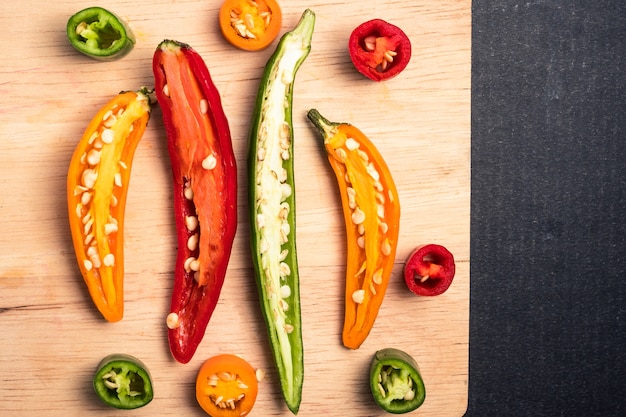 Mélange coloré de piments chili sur un plateau en bois sur fond noir.