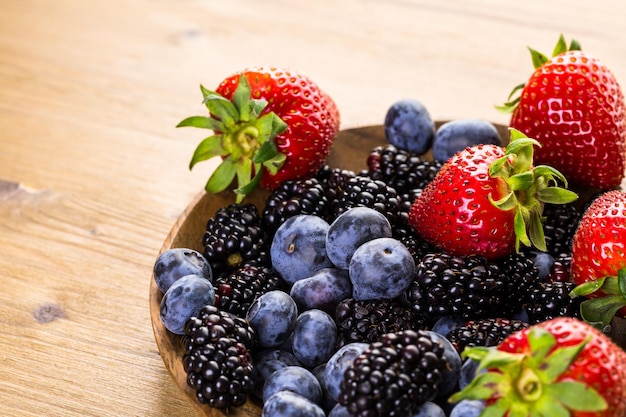 Mélange de fruits frais biologiques dans un bol en bois sur la table.