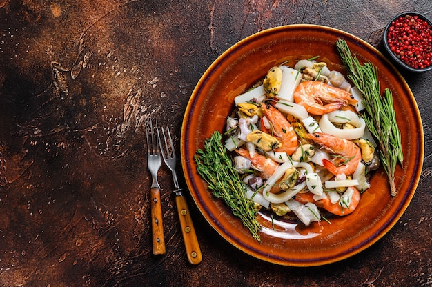 Mélange de fruits de mer crus avec crevettes, crevettes, moules, calmars et poulpes sur une planche à découper. Espace de copie