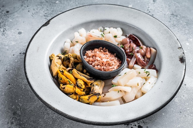 Mélange de fruits de mer crus dans une assiette rustique Fond gris Vue de dessus