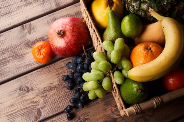 Mélange de fruits tropicaux exotiques colorés juteux frais dans le panier sur la vue de dessus de fond en bois