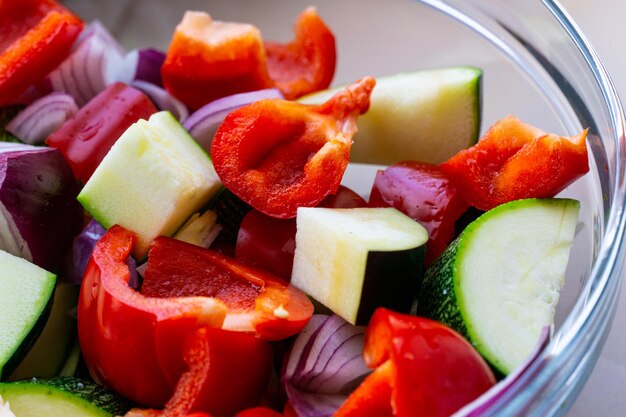 Un mélange de légumes dans un bol en verre courgette aubegrine poivron rouge et oignon rouge