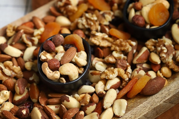 Mélange de noix et de fruits secs sur une planche de bois et dans un bol Bonbons sains