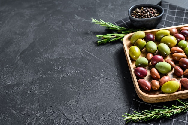 Mélange d'olives marinées colorées avec un os. Fond noir. Vue de dessus. Espace pour le texte