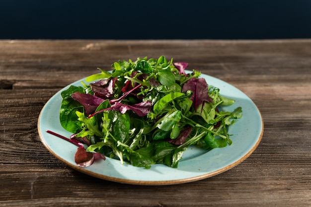 Mélange de salade d'herbes fraîches dans une assiette sur une table en bois