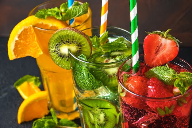 Mélange de trois délicieuses limonades froides aux couleurs vives de kiwi et d'orange et de fraise à la menthe sur la table