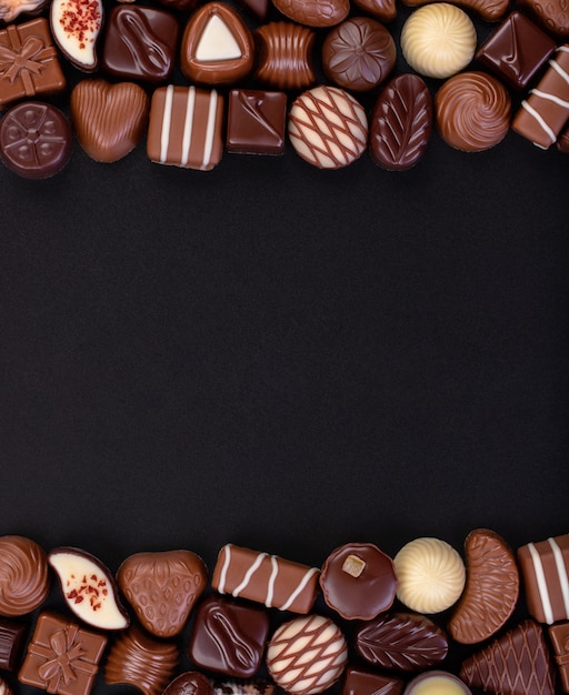 Mélanger les bonbons au chocolat et autres douceurs sur fond de tableau noir, cadre de nourriture sucrée