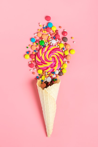 mélanger des bonbons au chocolat colorés renversés dans un cône de gaufre à la crème glacée rose poser