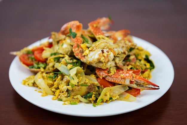 Mélanger du crabe frit avec de la poudre de curry, closeup, cuisine thaïlandaise sur fond en bois